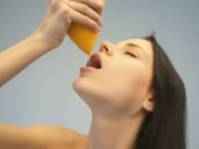 Adolescente nudo che beve succo d'arancia
